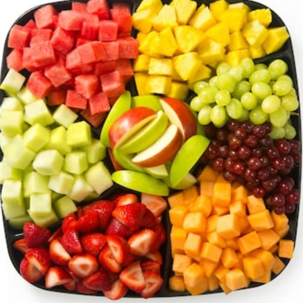 A black platter filled with colorful diced fruits, including watermelon, pineapple, grapes, apples, strawberries, and cantaloupe.