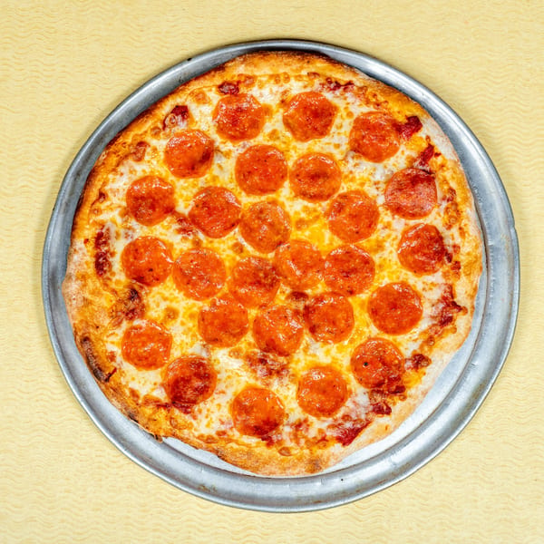 A whole pepperoni pizza on a metal pan, centered on a yellow wavy background.